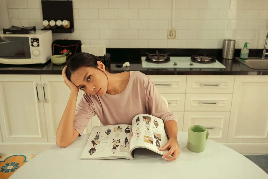 Woman at a kitchen table repeating a digit sequence back into a tablet, notepad pushed aside